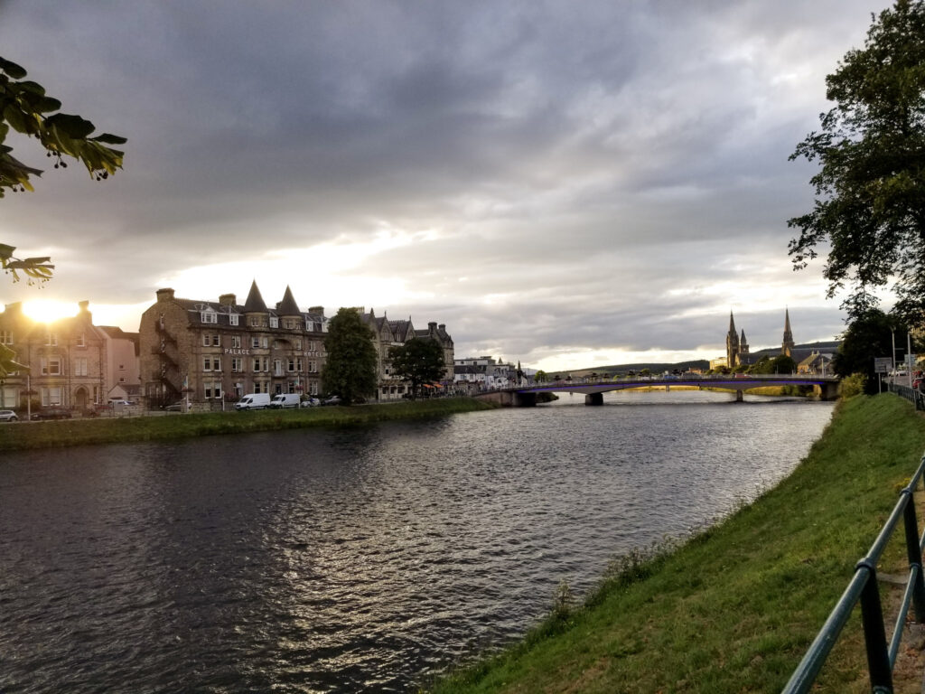 A photo of the sunset over Inverness in Scotland with a Scottish Loch in the foreground